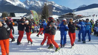 Skilehrer mit großer Kindergruppe bei Aufwärmübungen | © Skischule Edelweiß